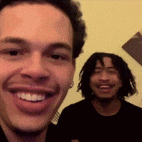 A Man With Dreadlocks Is Smiling Next To Another Man With Dreadlocks GIF