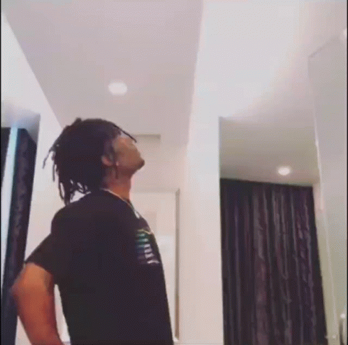 A Man With Dreadlocks Is Standing In A Room With His Hands On His Hips . GIF