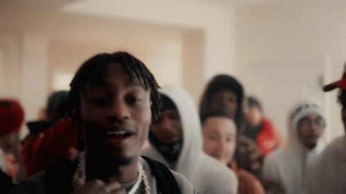 A Man With Dreadlocks Is Standing In Front Of A Crowd Of People Wearing Hoodies GIF