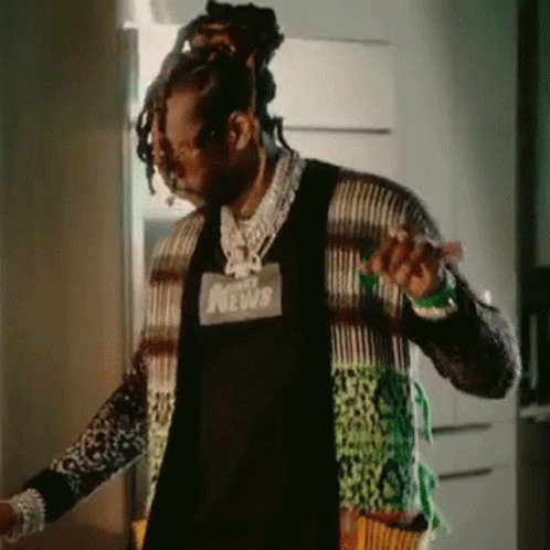 A Man With Dreadlocks Is Standing In Front Of A Door Wearing A Sweater . GIF