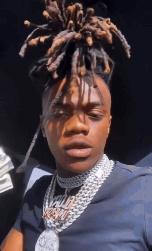 A Man With Dreadlocks Is Wearing A Necklace That Says ' King ' On It . GIF