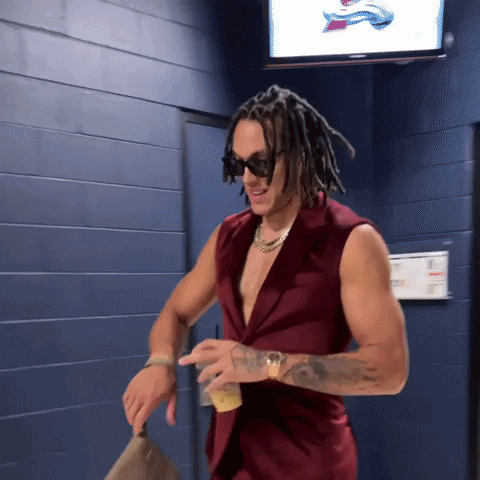 A Man With Dreadlocks Is Wearing A Red Vest GIF
