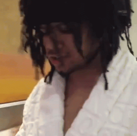 A Man With Dreadlocks Is Wearing A White Robe And A Black Hat . GIF