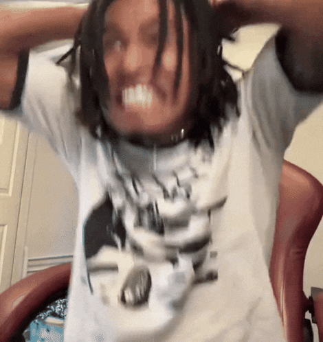 A Man With Dreadlocks Is Wearing A White Shirt With A Picture Of A Man 'S Face On It GIF