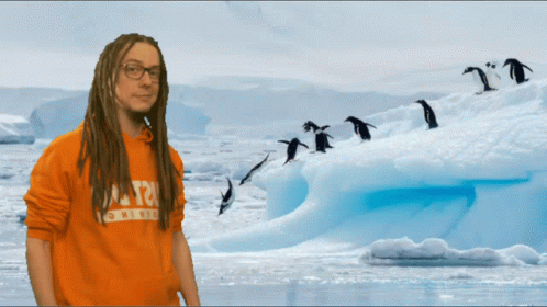 A Man With Dreadlocks Is Wearing An Orange Shirt That Says T2 On The Front GIF