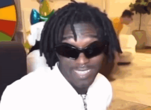 A Man With Dreadlocks Is Wearing Sunglasses And A White Shirt . GIF