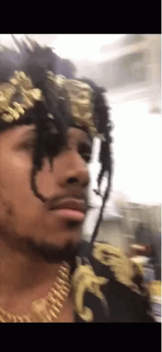 A Man With Dreadlocks Wearing A Gold Headband And Necklace GIF