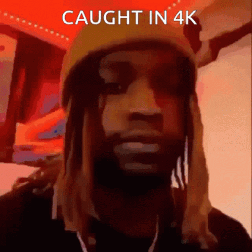 A Man With Dreadlocks Wearing A Yellow Hat With The Words Caught In 4K Below Him GIF