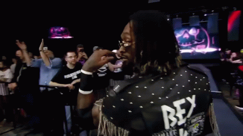 A Man With Dreadlocks Wearing Sunglasses Is Smiling In Front Of A Crowd . GIF