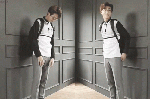 A Man With Glasses And A Backpack Is Standing In A Corner GIF