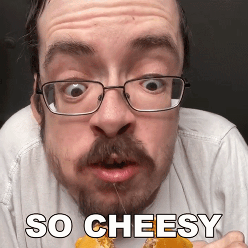 A Man With Glasses And A Beard Is Eating Cheese With The Words So Cheesy Above Him GIF