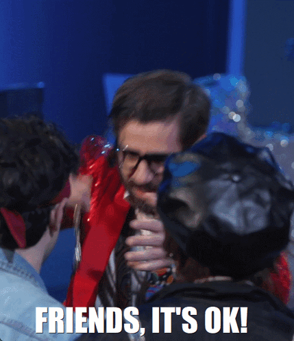 A Man With Glasses And A Beard Is Holding A Necklace With The Words Friends It 'S Ok On The Bottom GIF