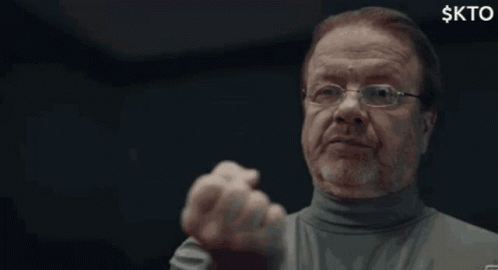 A Man With Glasses And A Beard Is Making A Funny Face With His Fist In The Air . GIF