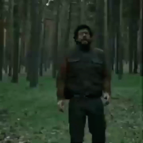 A Man With Glasses And A Beard Is Screaming In A Field . GIF