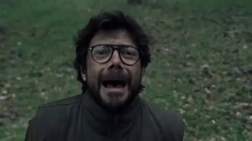 A Man With Glasses And A Beard Is Screaming In A Field . GIF