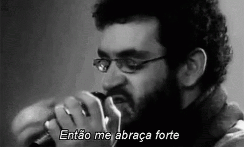 a man with glasses and a beard is singing into a microphone .