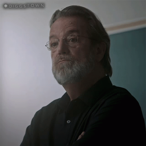 A Man With Glasses And A Beard Is Standing In Front Of A Green Board That Says #Diggstown GIF