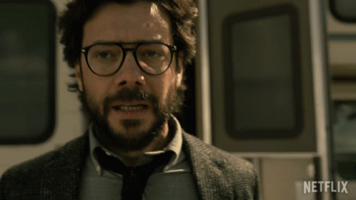 A Man With Glasses And A Beard Is Standing In Front Of A Netflix Logo GIF