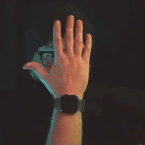 A Man With Glasses And A Beard Is Wearing A Beanie And Covering His Mouth With His Hand . GIF