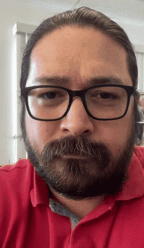 A Man With Glasses And A Beard Is Wearing A Red Polo Shirt GIF