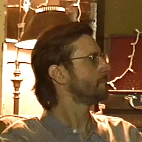 A Man With Glasses And A Beard Looks To His Left GIF