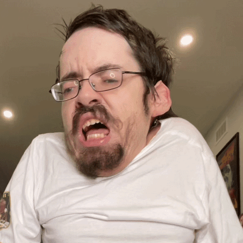 A Man With Glasses And A Beard Making A Face GIF
