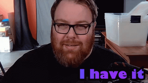 A Man With Glasses And A Beard Says " I Have It " In Purple Letters GIF