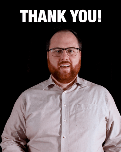 A Man With Glasses And A Beard Stands In Front Of A Sign That Says Thank You GIF