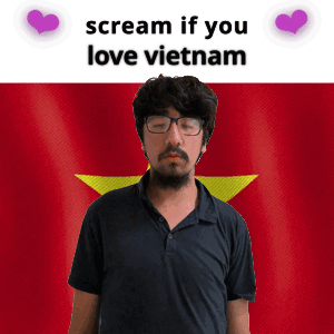 A Man With Glasses And A Beard Stands In Front Of A Vietnam Flag GIF