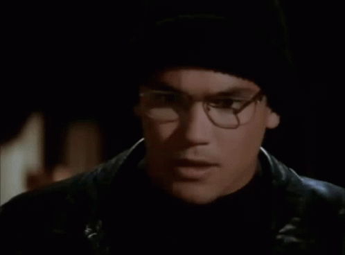 A Man With Glasses And A Black Hat Is Holding A Blue Object In Front Of His Face GIF
