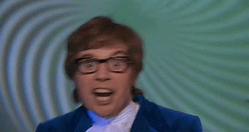 A Man With Glasses And A Blue Suit Is Making A Funny Face . GIF