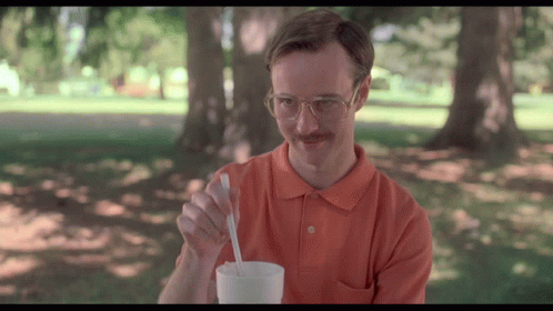 A Man With Glasses And A Mustache Is Holding A Spoon In A Cup GIF
