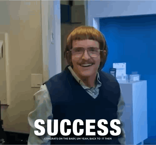 A Man With Glasses And A Mustache Is Standing In Front Of A Sign That Reads Success GIF