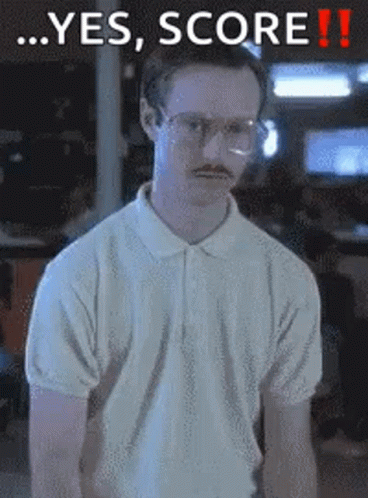 A Man With Glasses And A Mustache Is Standing In Front Of A Sign That Says Yes Score GIF