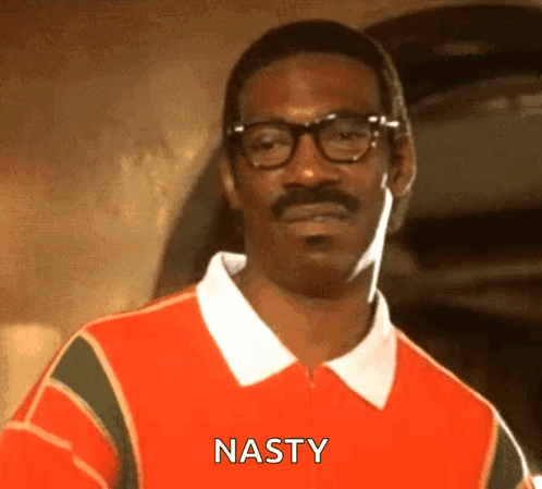 A Man With Glasses And A Mustache Is Wearing An Orange Shirt That Says Nasty On It . GIF