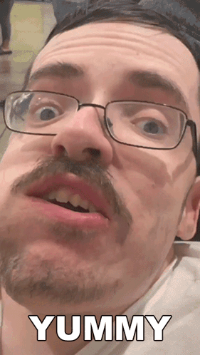 A Man With Glasses And A Mustache Says Yummy In White Letters GIF