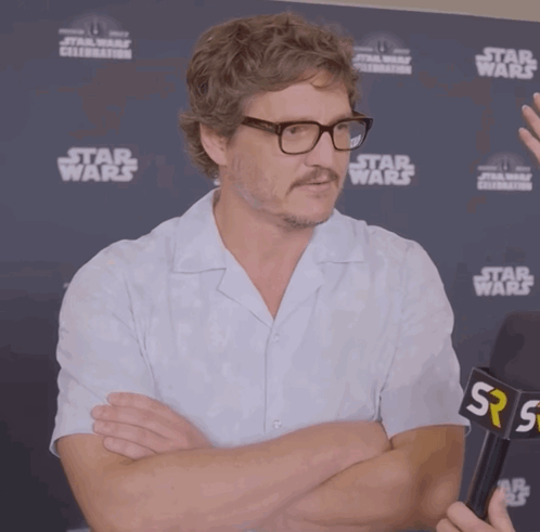 A Man With Glasses And A Mustache Stands In Front Of A Star Wars Sign GIF