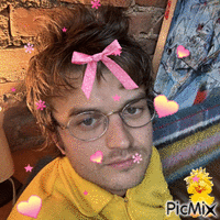 A Man With Glasses And A Pink Bow In His Hair Is Surrounded By Hearts And Stars GIF