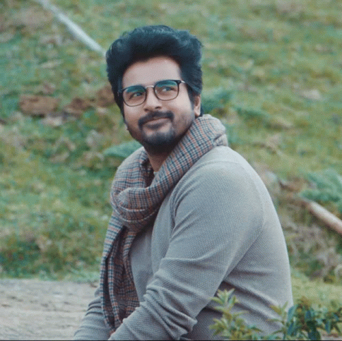 A Man With Glasses And A Scarf Around His Neck Smiles For The Camera GIF