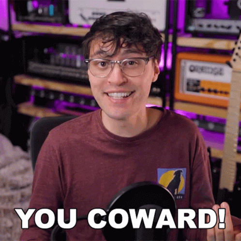 A Man With Glasses And A Shirt That Says You Coward GIF
