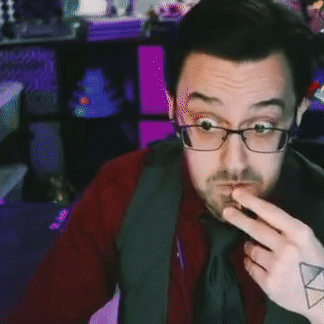 A Man With Glasses And A Tattoo On His Arm Is Pointing At Something . GIF