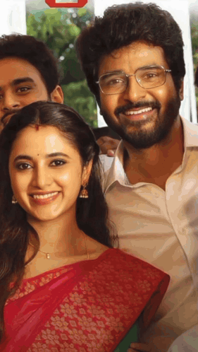 A Man With Glasses And A Woman In A Red Saree Smile For A Picture GIF
