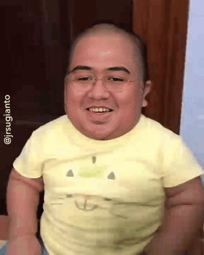 A Man With Glasses And A Yellow Shirt Is Smiling GIF