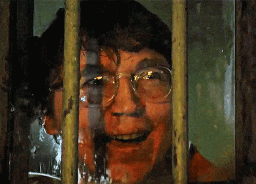 A Man With Glasses Is Behind Bars With His Mouth Open GIF
