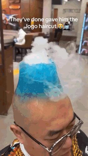 A Man With Glasses Is Getting A Haircut That Looks Like A Mountain With Smoke Coming Out Of It . GIF