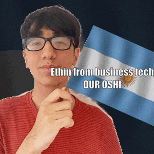 A Man With Glasses Is Holding A Flag With The Words " Ethin From Business Tech Our Oshi " Written On It GIF