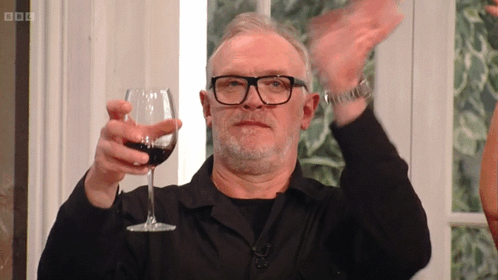 A Man With Glasses Is Holding A Glass Of Wine In His Hand GIF