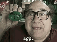 A Man With Glasses Is Holding A Green Egg That Says Patty 'S Putts On It GIF