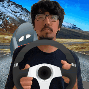 A Man With Glasses Is Holding A Steering Wheel In Front Of A Mountain GIF