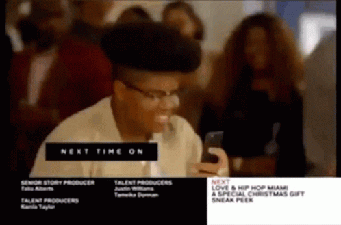 A Man With Glasses Is Looking At His Phone Next To A Sign That Says " Next Time On " GIF